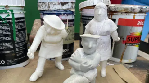 White little clay sculptures not bigger than the pots of paint that surround them sit on a table. The scenery artists use these to refer to.