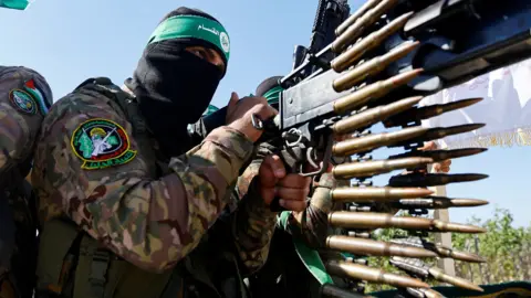 A Palestinian fighter from the armed wing of Hamas holds a weapon