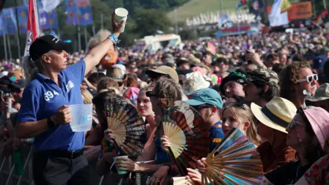 EPA Staff handing out water to festival goers at Glastonbury, who are waving fans