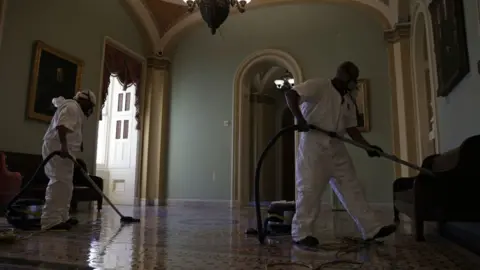 Getty Images A cleaning crew vacuums the floor of a hallway at the US Capitol 7 January