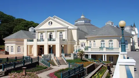 MANX SCENES The outside of the Villa Marina, which has walkways leading to the gardens. Red and yellow lowers in the flower beds are in bloom alongside ornate green painted railings.
