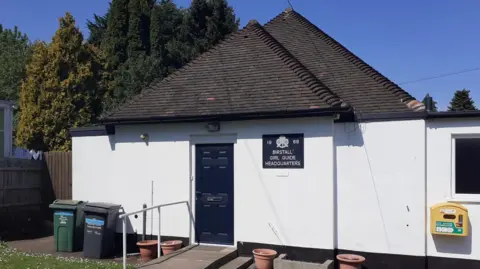 BBC White building with brown slate roof.