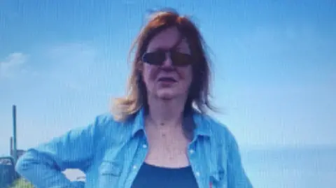 Police Scotland A woman with long hair and dark glasses in a blue denim shirt with a blue T-shirt underneath