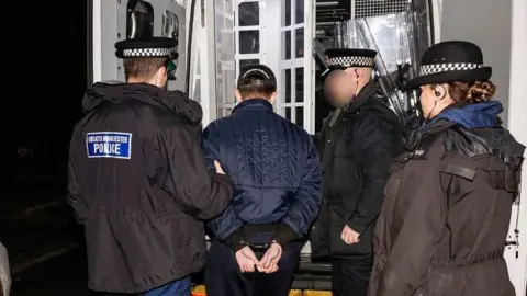 Greater Manchester Police Police officers arrest a man and put him in a police van
