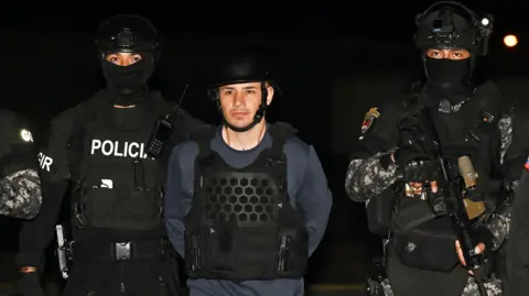 Getty Images Ecuadorean police escort Ángel Esteban Aguilar in the cover of darkness. All wear tactical gear.
