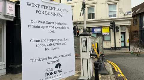 Julia Gregory/BBC A sign which reads West Street is open for business and encourages people to continue visiting shops cafes and pubs on foot while the road is closed to cars