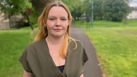 Whitehead pictured in a park. She has brown hair and is wearing a green jacket.