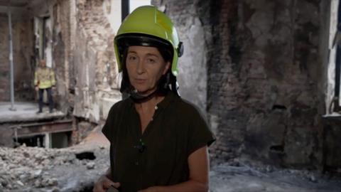 Sarah Rainsford wearing a hard hat in destroyed building