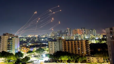 Reuters Streaks of light are seen from Ashkelon as Israel's Iron Dome anti-missile system intercepts rockets launched from the Gaza Strip towards Israel (15 May 2021)