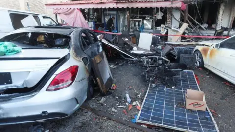 Reuters Damaged cars and a cafe which has a single man inspecting the aftermath of the strike