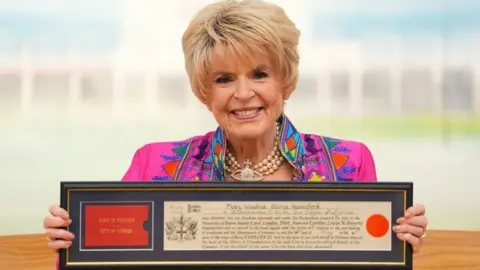 Gloria Hunniford holding her certificate showing her Freedom of the City of London
