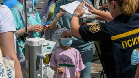 EPA: A psychologist gestures with a little girl at the site of a rocket attack on the Ochmadyt children's hospital in Kyiv, Ukraine, on July 08, 2024, during the Russian invasion.