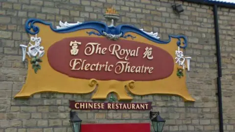 Google A photo of the cartouche before it fell into disrepair. It reads "The Royal Electric Theatre" in golden letters on a red and yellow background with hints of blue and white.