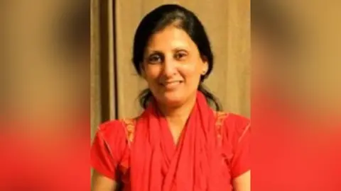 Missing People A woman in a red sari smiling at the camera