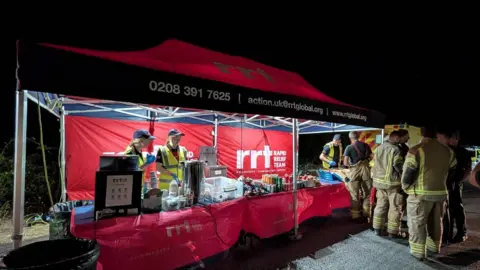 Rapid Relief Team A red tent with volunteers serving food to firefighters.