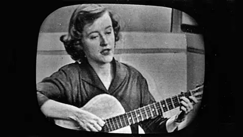 The Musick Group Connie Converse seen on a TV screen playing the guitar in 1954