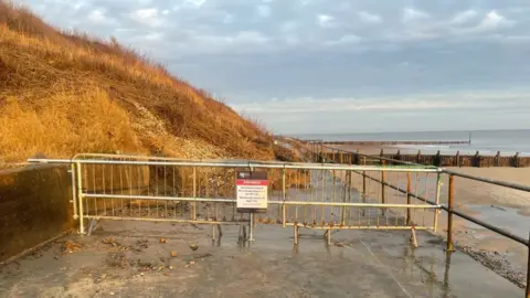 North Norfolk District Council A cliff-fall shows debris on a path and barriers and signs warning people to stay away