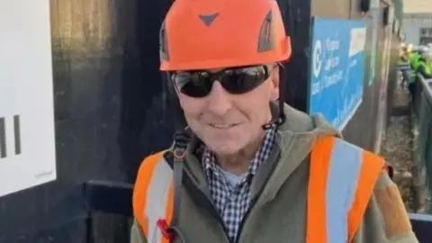 Glen Edwards wearing an orange hard hat, high-vis vest and sunglasses.