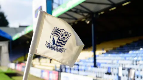 Getty Images A white corner flag with the blue Southend United crest on it. A stand with blue and yellow seats is pictured in the background.