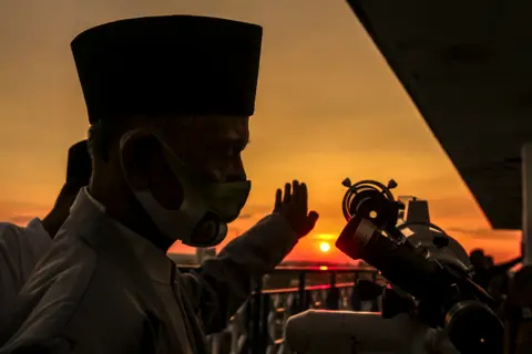 Shutterstock Muslims use a telescope as the sun sets