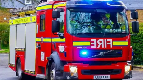 Oxfordshire Fire and Rescue service engine with lights flashing.