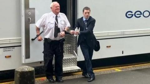 Liam Stimpson coming out of a police van and is handcuffed to a prison officer