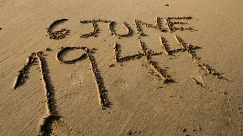 Carmen Martínez Torrón/Getty Images Date of D-Day landings written in sand on beach in Normandy, France