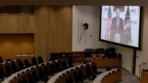 Reuters Donald Trump appears on a video screen to an empty conference room