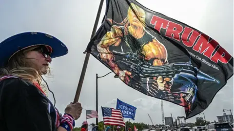 Getty Images A Florida Trump fan holds a flag depicting him as Rambo, the action star