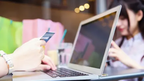 Getty Images woman holding credit card at laptop