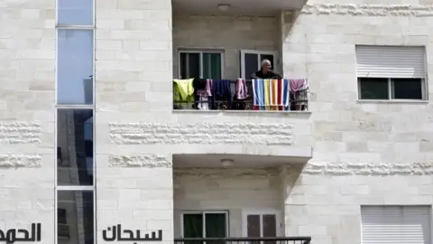 EPA A man looks out from his balcony in Amman, Jordan