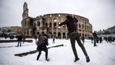 EPA People take part in a snowball fight in front of the Colosseum covered by snow during a snowfall in Rome, Italy, 26 February 2018.