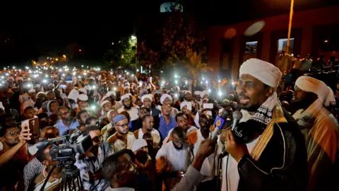 Getty Images Sudanese hardline cleric Mohamed Ali Jazuli speaks as supporters of Islamist movements rally in front of the Presidential Palace in downtown Khartoum on May 18, 2019. - Talks between Sudan's ruling military council and protesters are set to resume, army rulers announced, as Islamic movements rallied for the inclusion of sharia in the country's roadmap.