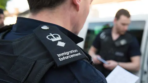 Getty Images Immigration enforcement officers raid a home in Southall in 2015