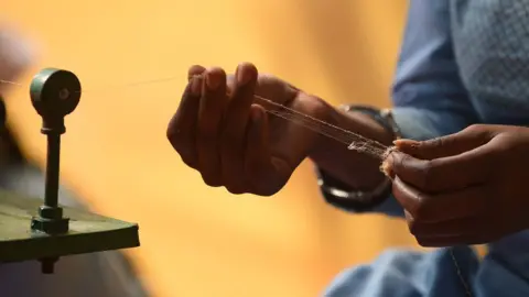 Getty Images A spinner extracts thread from a seed