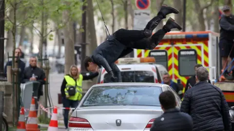 Getty Images Tom Cruise hanging upside down attached to wires