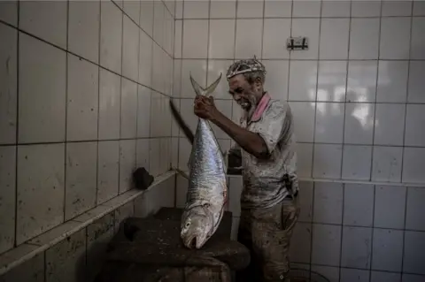 Sebnem Coskun/Getty Images A salesman prepares sea products on sale at Darajani fish market in Stone Town of Zanzibar, Tanzania - Friday 23 June 2023