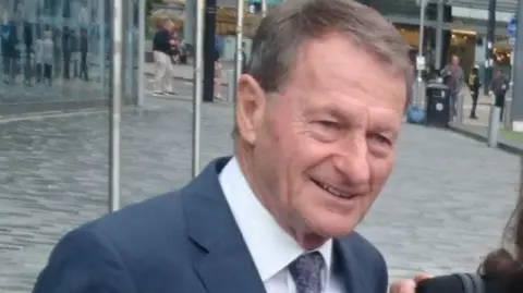 Paul Burnell/BBC Roger Hunt at the opening of the World Cup Walk of Fame at the National football Museum Manchester he had greying brownhair, a blue suit, white shirt and blue paisley tie.
