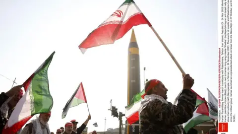 EPA Iranians holding the national flag and red bandanas on their heads with a missile pointing skywards
