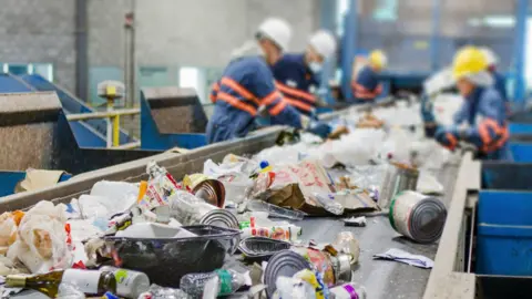 Workers at a recycling plant processing recycling materials such as cans and wrappers