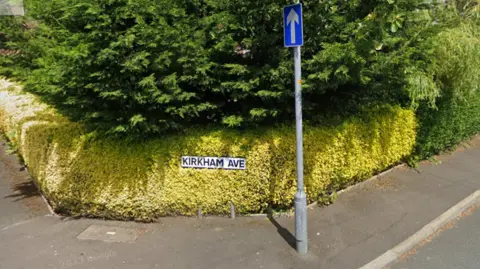 A street view of a close with a green bush and a road sign reading 'KIRKHAM AVE'.