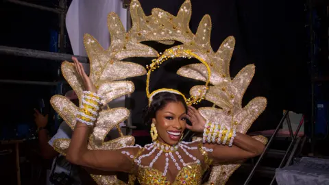 Emmanuel Adegboye / EPA Un'immagine di una concorrente di Miss Universo che indossa un abito bianco e oro nel backstage a Lagos, Nigeria - sabato 31 agosto 2024