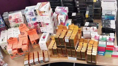 South Yorkshire Police Hundreds of small boxes of vapes on a desk.