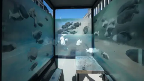 PA Media Possible Banksy artwork of a shoal of fish on the windows of a police sentry box in London