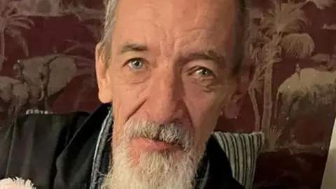 Wayne Woodgate is pictured as a man with a grey beard