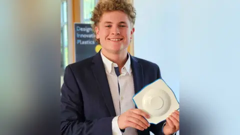 Harry Wragg looking at the camera smiling and holding his CPR prototype
