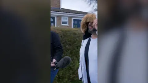 BBC reporter with a microphone confronts a man who's been reselling driving test slots at overinflated prices