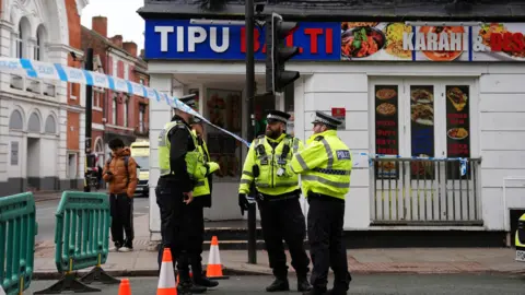 PA Media A group of police officers standing in front of a kebab shop