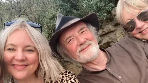 Adam Riding John Riding poses in a group picture with his daughter and wife