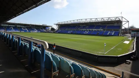 Getty Images A wide angle shot of the inside of Peterborough United's Weston Homes stadium in London Road. There is a large green pitch and three of the stadium's stands, which have blue seats.